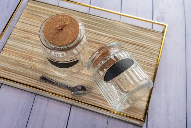 Two empty glass storage jars with blank chalk labels and a spoon on a woven tray